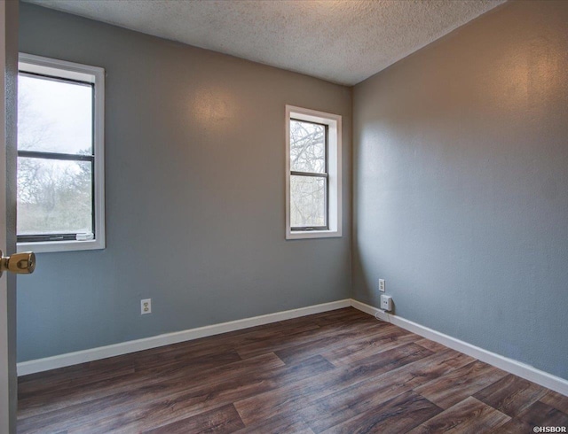 empty room featuring dark wood-style flooring, a textured ceiling, and baseboards