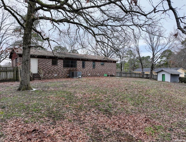 back of property with entry steps, an outbuilding, fence, a storage unit, and cooling unit