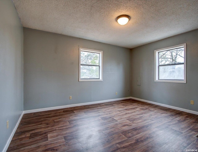 unfurnished room with dark wood-type flooring, a textured ceiling, and baseboards