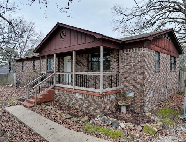 view of front of property featuring covered porch, brick siding, and crawl space