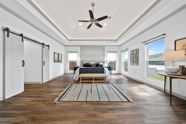 bedroom featuring visible vents, a barn door, a high ceiling, wood finished floors, and access to outside