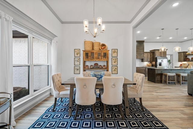 dining area featuring light wood finished floors, a wealth of natural light, an inviting chandelier, and ornamental molding