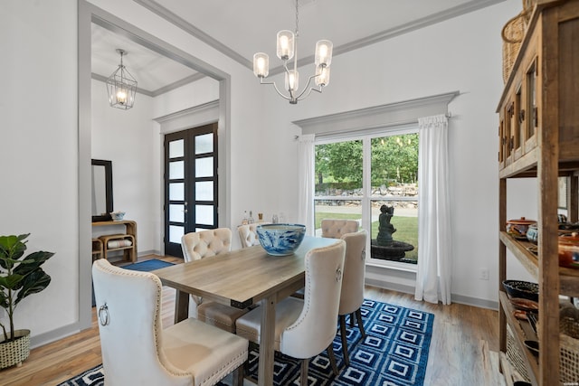 dining area featuring light wood-type flooring, baseboards, a notable chandelier, and ornamental molding