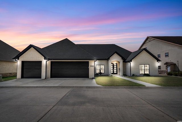 view of front facade with concrete driveway, a yard, brick siding, and a garage