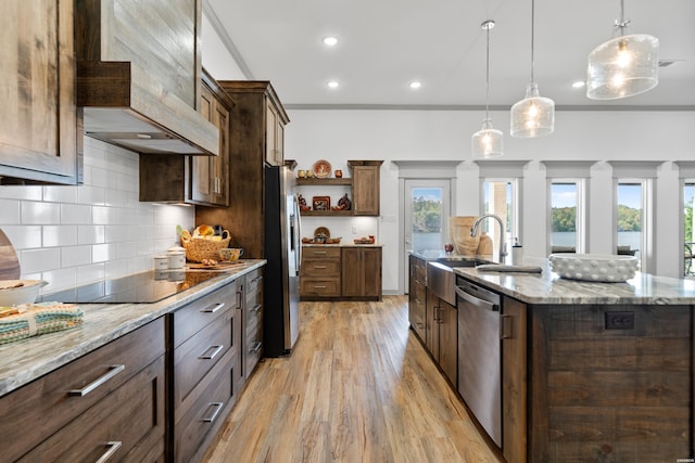 kitchen with an island with sink, appliances with stainless steel finishes, light wood-style floors, custom exhaust hood, and open shelves