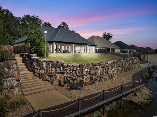 rear view of property featuring a patio area, a lawn, and fence