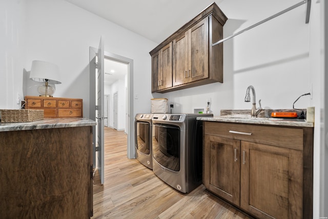 laundry room with cabinet space, independent washer and dryer, light wood finished floors, and a sink