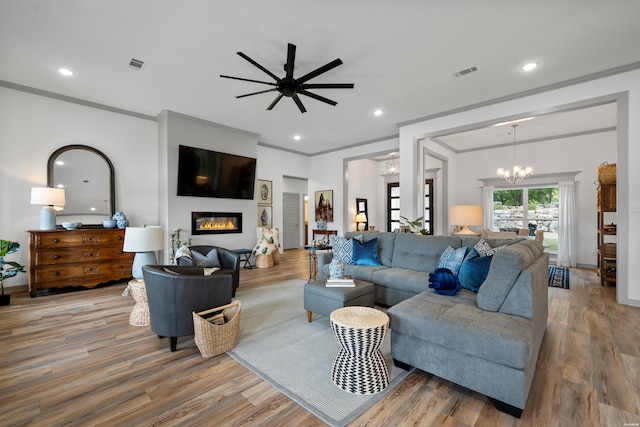 living area featuring a glass covered fireplace, recessed lighting, wood finished floors, and visible vents