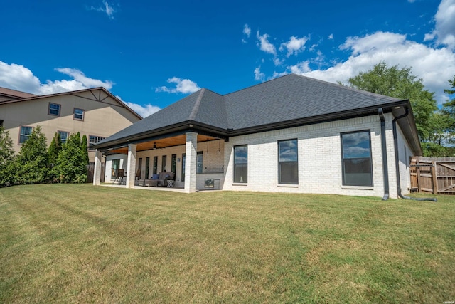 back of property featuring a lawn, fence, brick siding, ceiling fan, and a patio area