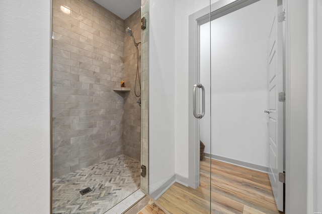 bathroom with a shower stall, baseboards, and wood finished floors