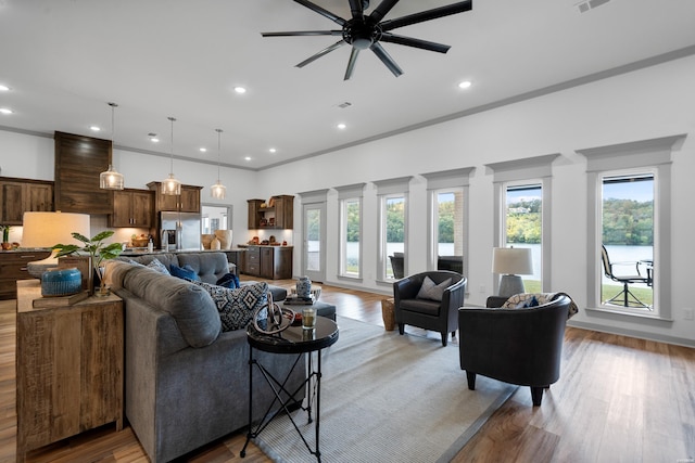 living room with crown molding, recessed lighting, a ceiling fan, and light wood finished floors