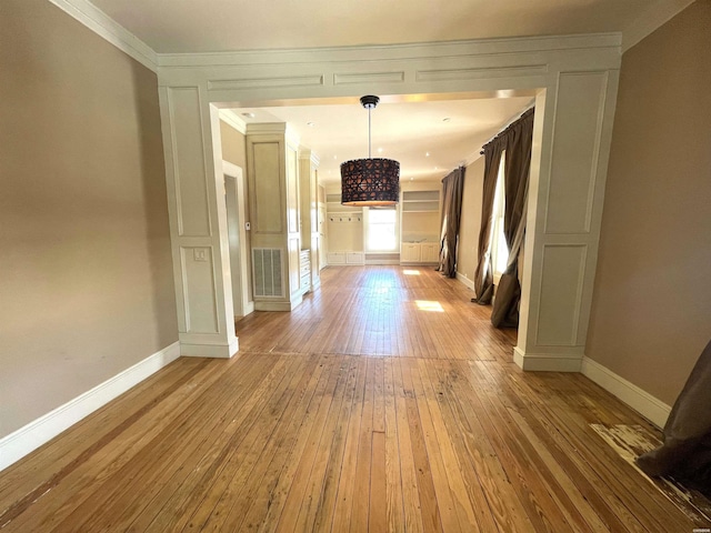 corridor featuring baseboards, visible vents, wood finished floors, and ornamental molding