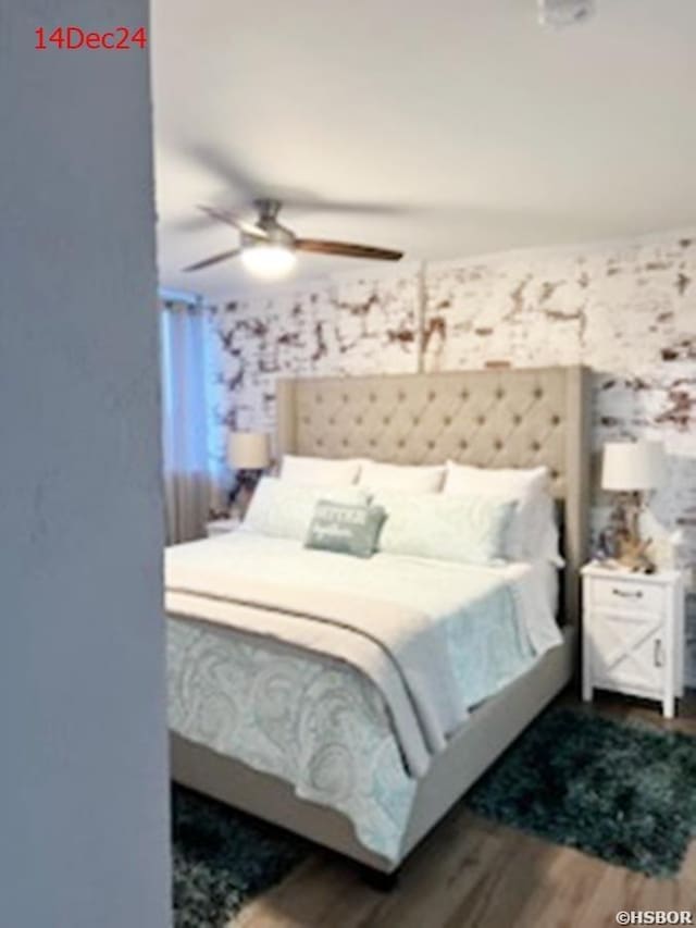 bedroom with wallpapered walls, a ceiling fan, and wood finished floors