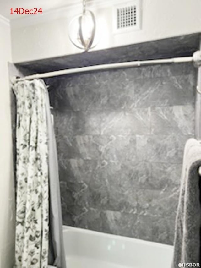 room details featuring shower / tub combo, visible vents, and crown molding