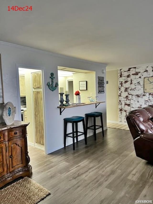 living area featuring light wood finished floors, baseboards, and ornamental molding