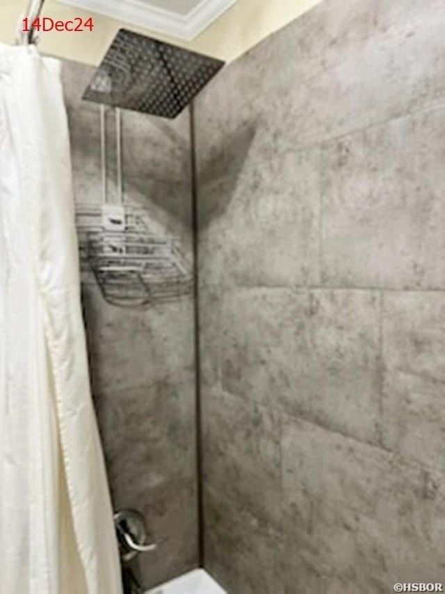 bathroom with a tile shower and crown molding