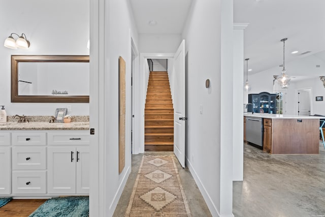 corridor featuring baseboards, lofted ceiling, stairs, concrete floors, and a sink