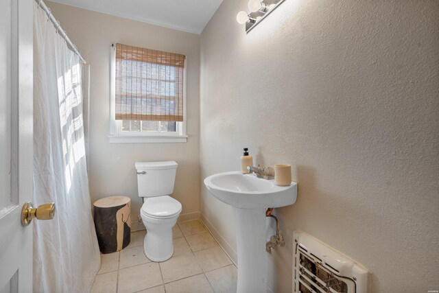 bathroom featuring baseboards, heating unit, toilet, and tile patterned floors