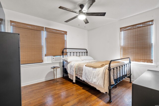 bedroom with cooling unit, wood finished floors, a ceiling fan, and baseboards