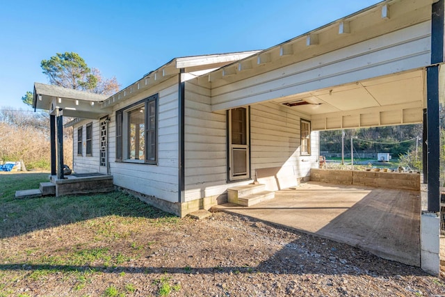 view of property exterior featuring entry steps, a patio area, driveway, and a carport