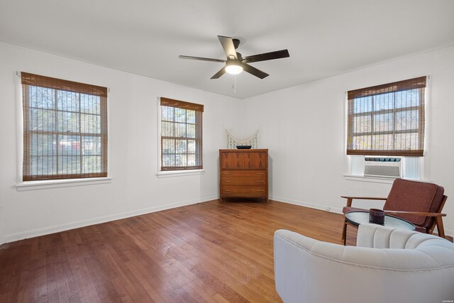 living area with light wood finished floors, ceiling fan, baseboards, and cooling unit