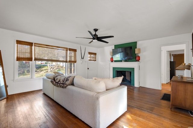 living area with a fireplace, wood finished floors, a ceiling fan, and baseboards