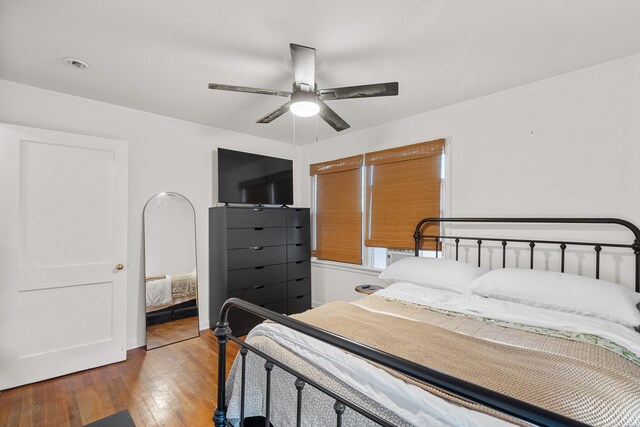 bedroom with visible vents, wood finished floors, a ceiling fan, and baseboards