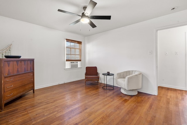 sitting room featuring cooling unit, ceiling fan, baseboards, and wood finished floors