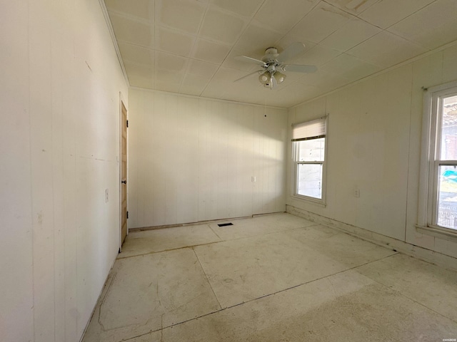 unfurnished room featuring ceiling fan, visible vents, and a wealth of natural light