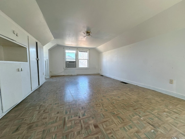 additional living space featuring cooling unit, visible vents, vaulted ceiling, and baseboards