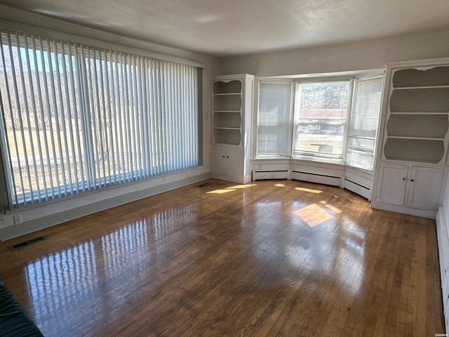 unfurnished room with visible vents and hardwood / wood-style flooring