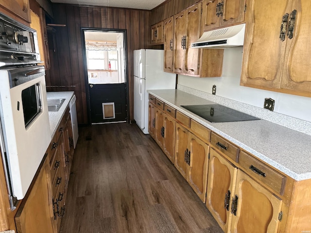 kitchen featuring ventilation hood, dark wood finished floors, white appliances, and brown cabinets