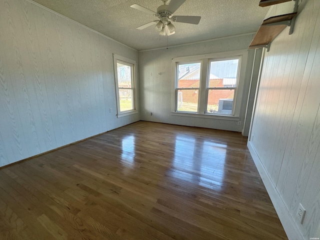 unfurnished room featuring a textured ceiling, a ceiling fan, dark wood-style flooring, and ornamental molding