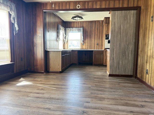 interior space featuring wooden walls, a textured ceiling, light countertops, and wood finished floors