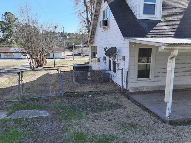 view of yard with a gate, a patio area, fence, and central AC unit