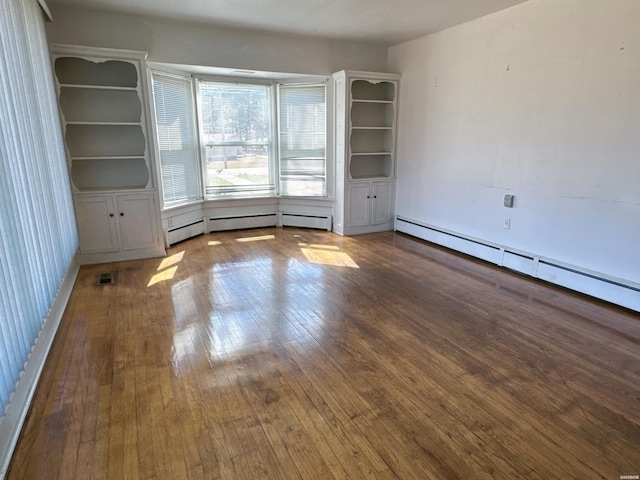 empty room with hardwood / wood-style flooring, a baseboard radiator, visible vents, and a baseboard heating unit