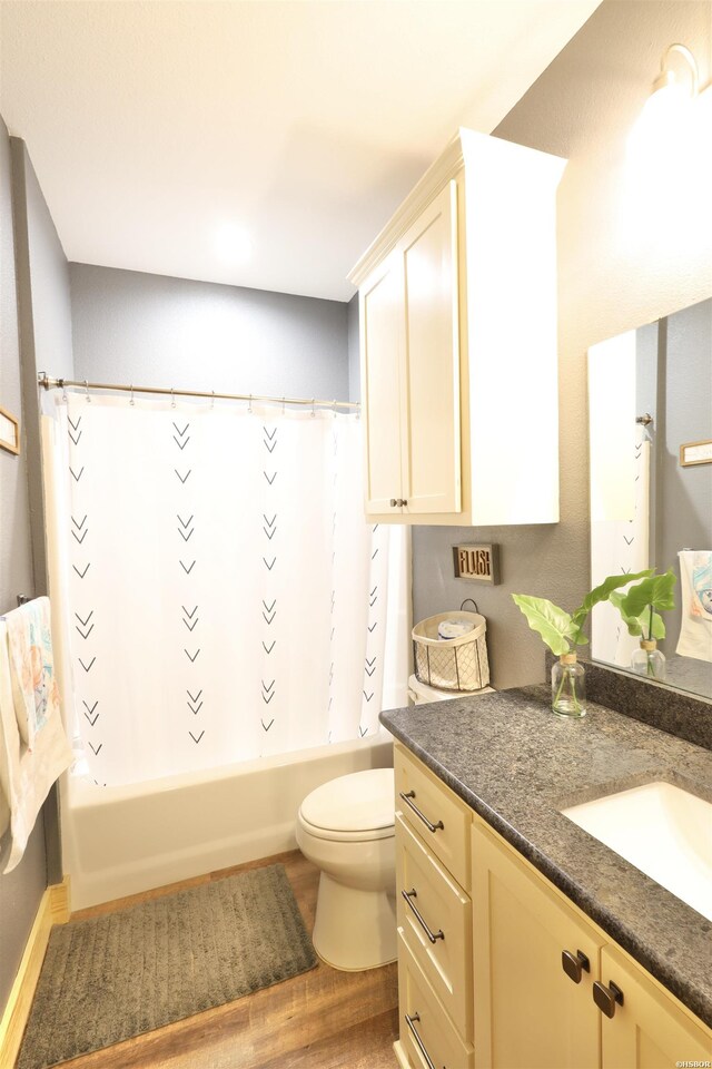 bathroom featuring toilet, wood finished floors, vanity, and shower / tub combo with curtain