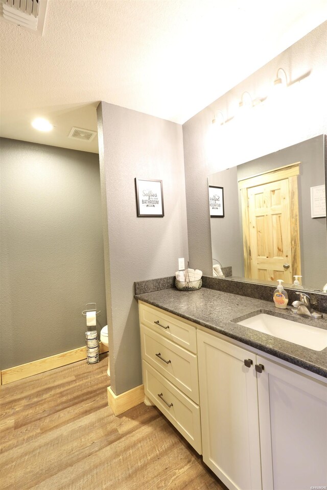 bathroom with baseboards, visible vents, wood finished floors, and vanity