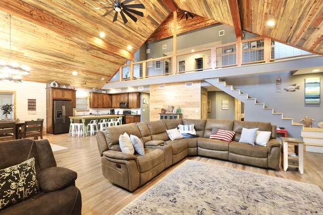 living room featuring high vaulted ceiling, light wood finished floors, wood walls, and wood ceiling