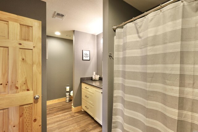 bathroom with baseboards, visible vents, wood finished floors, a textured ceiling, and vanity