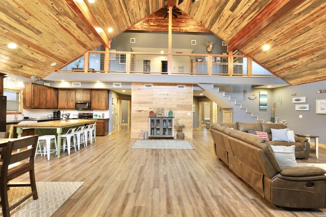 living area with stairway, light wood-type flooring, and wood ceiling