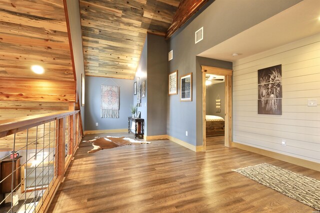 hall with baseboards, visible vents, wood ceiling, wood finished floors, and vaulted ceiling