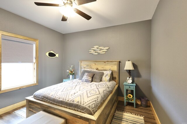 bedroom with ceiling fan, wood finished floors, and baseboards