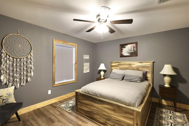 bedroom with dark wood-style floors, ceiling fan, visible vents, and baseboards