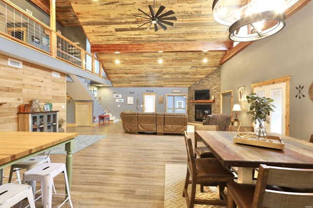 dining room with wooden ceiling, a fireplace, stairway, and high vaulted ceiling