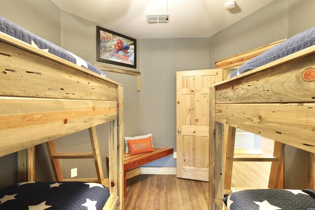 bedroom with wood finished floors, visible vents, and baseboards