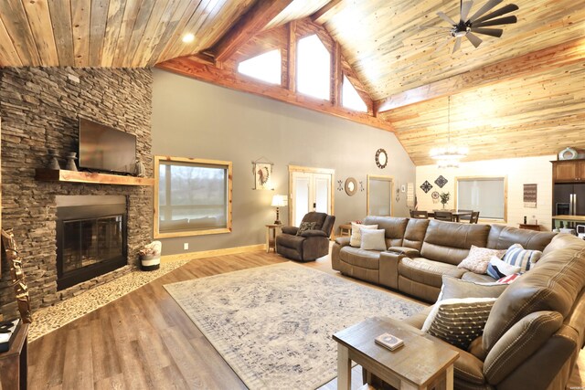 living room with wood ceiling, a healthy amount of sunlight, a stone fireplace, and wood finished floors