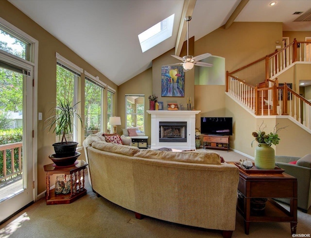 carpeted living room featuring a skylight, baseboards, stairs, a fireplace, and high vaulted ceiling