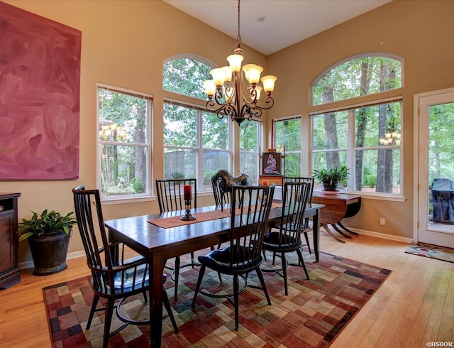 dining area with high vaulted ceiling, plenty of natural light, light wood-style flooring, and baseboards