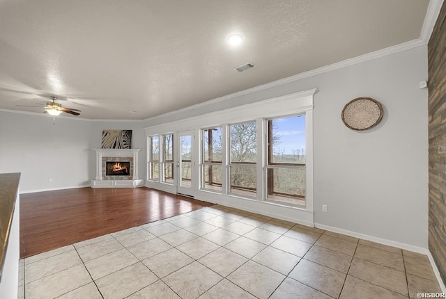 unfurnished living room featuring ceiling fan, visible vents, ornamental molding, and light tile patterned floors